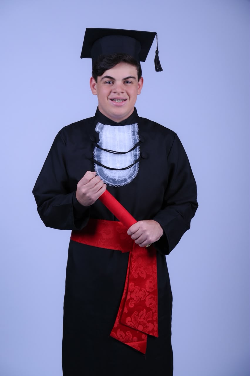 Yan com beca e capelo, segurando o diploma